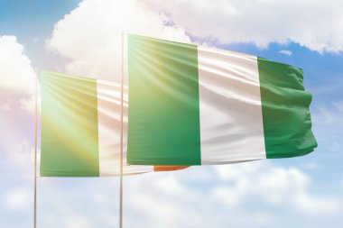Sunny blue sky and flags of nigeria and ireland