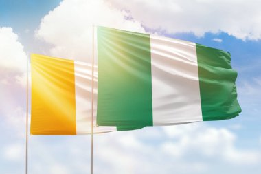 Sunny blue sky and flags of nigeria and ivory coast