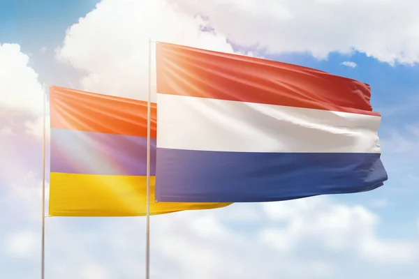 Sunny blue sky and flags of netherlands and armenia