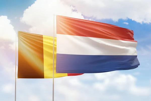 Sunny blue sky and flags of netherlands and belgium