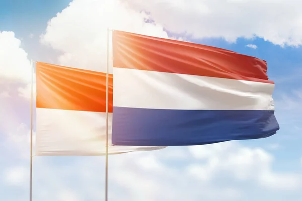 Sunny blue sky and flags of netherlands and indonesia