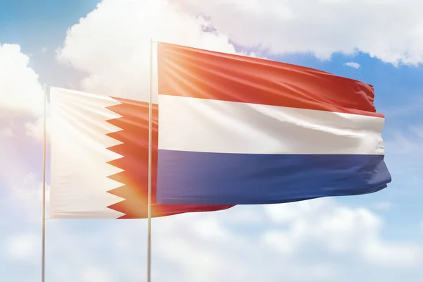 Sunny blue sky and flags of netherlands and qatar