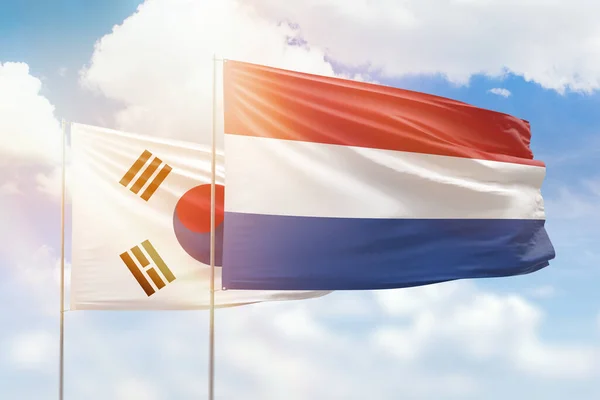 Sunny blue sky and flags of netherlands and south korea
