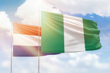 Sunny blue sky and flags of nigeria and netherlands