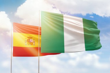 Sunny blue sky and flags of nigeria and spain