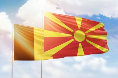 Sunny blue sky and flags of north macedonia and belgium