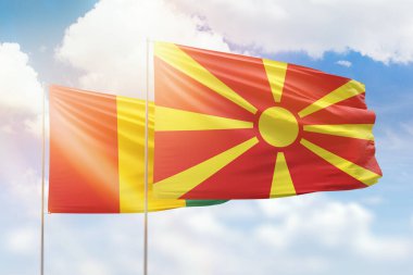 Sunny blue sky and flags of north macedonia and guinea