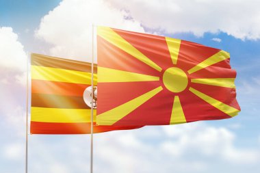 Sunny blue sky and flags of north macedonia and uganda