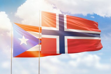 Sunny blue sky and flags of norway and puerto rico