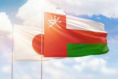 Sunny blue sky and flags of oman and japan