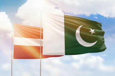 Sunny blue sky and flags of pakistan and latvia