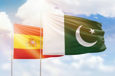 Sunny blue sky and flags of pakistan and spain