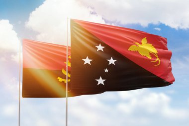 Sunny blue sky and flags of papua new guinea and angola