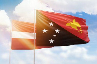 Sunny blue sky and flags of papua new guinea and latvia