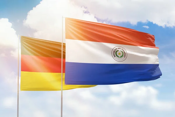 Sunny blue sky and flags of paraguay and germany