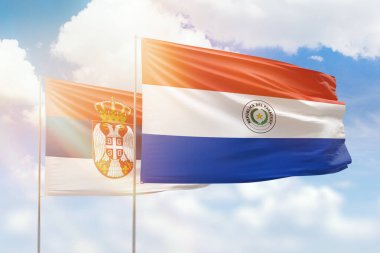 Sunny blue sky and flags of paraguay and serbia