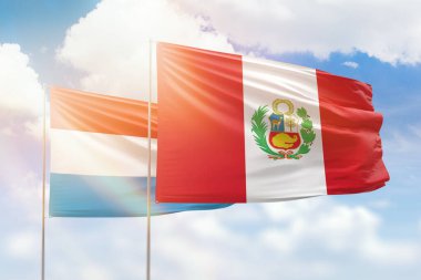 Sunny blue sky and flags of peru and luxembourg