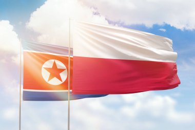 Sunny blue sky and flags of poland and north korea