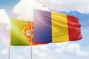 Sunny blue sky and flags of romania and portugal