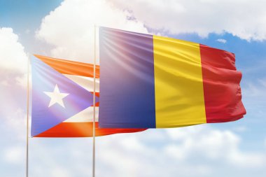 Sunny blue sky and flags of romania and puerto rico