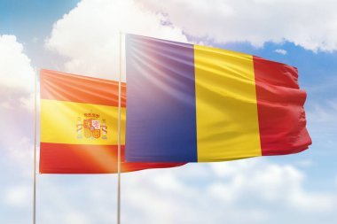 Sunny blue sky and flags of romania and spain