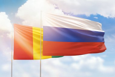 Sunny blue sky and flags of russia and guinea