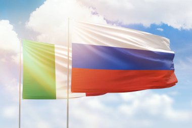 Sunny blue sky and flags of russia and italy