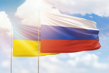Sunny blue sky and flags of russia and ukraine