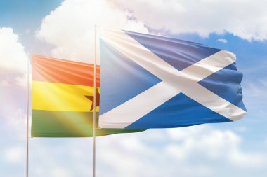 Sunny blue sky and flags of scotland and ghana