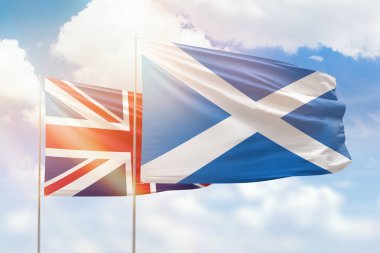 Sunny blue sky and flags of scotland and united kingdom