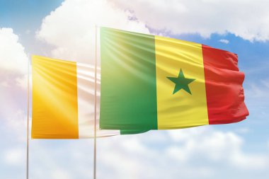 Sunny blue sky and flags of senegal and ivory coast
