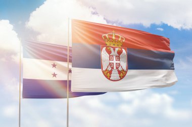 Sunny blue sky and flags of serbia and honduras