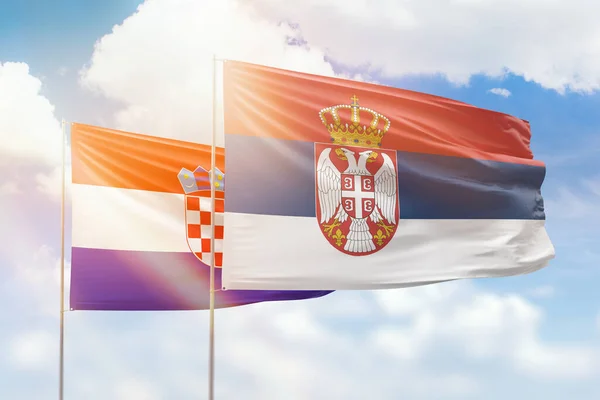 Sunny blue sky and flags of serbia and croatia