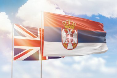 Sunny blue sky and flags of serbia and united kingdom