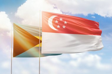 Sunny blue sky and flags of singapore and bahamas