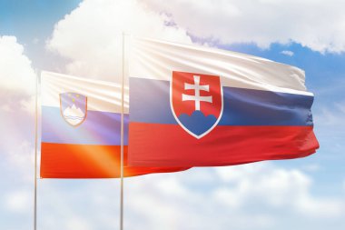Sunny blue sky and flags of slovakia and slovenia