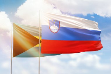 Sunny blue sky and flags of slovenia and bahamas