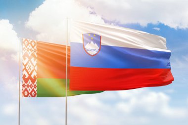 Sunny blue sky and flags of slovenia and belarus