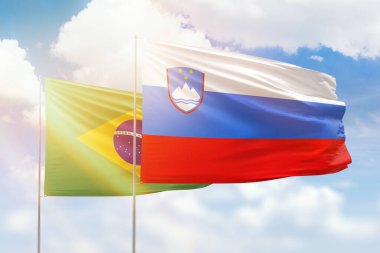 Sunny blue sky and flags of slovenia and brazil