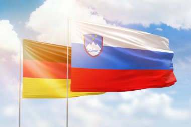 Sunny blue sky and flags of slovenia and germany