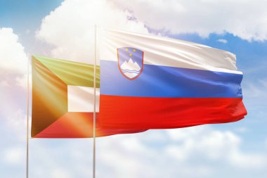 Sunny blue sky and flags of slovenia and kuwait