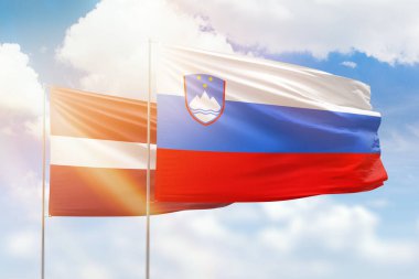 Sunny blue sky and flags of slovenia and latvia