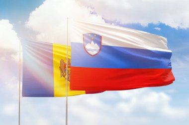 Sunny blue sky and flags of slovenia and moldova