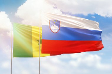 Sunny blue sky and flags of slovenia and senegal