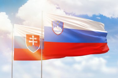 Sunny blue sky and flags of slovenia and slovakia