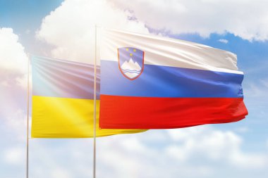 Sunny blue sky and flags of slovenia and ukraine