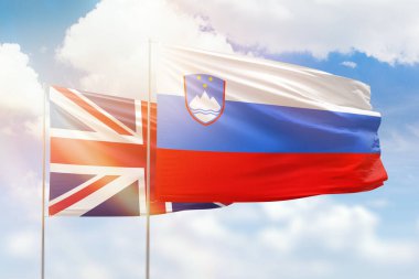 Sunny blue sky and flags of slovenia and united kingdom
