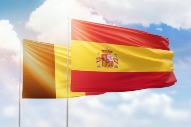 Sunny blue sky and flags of spain and belgium