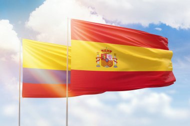 Sunny blue sky and flags of spain and colombia