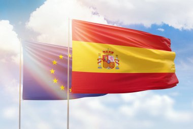Sunny blue sky and flags of spain and european union